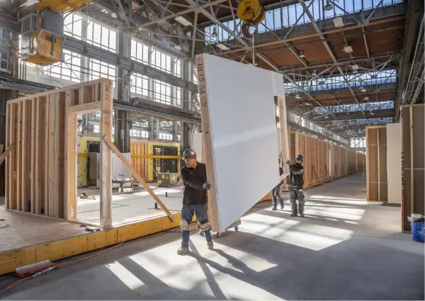 funcionarios-transportanto-parede-de-wood-frame-dentro-da-industria